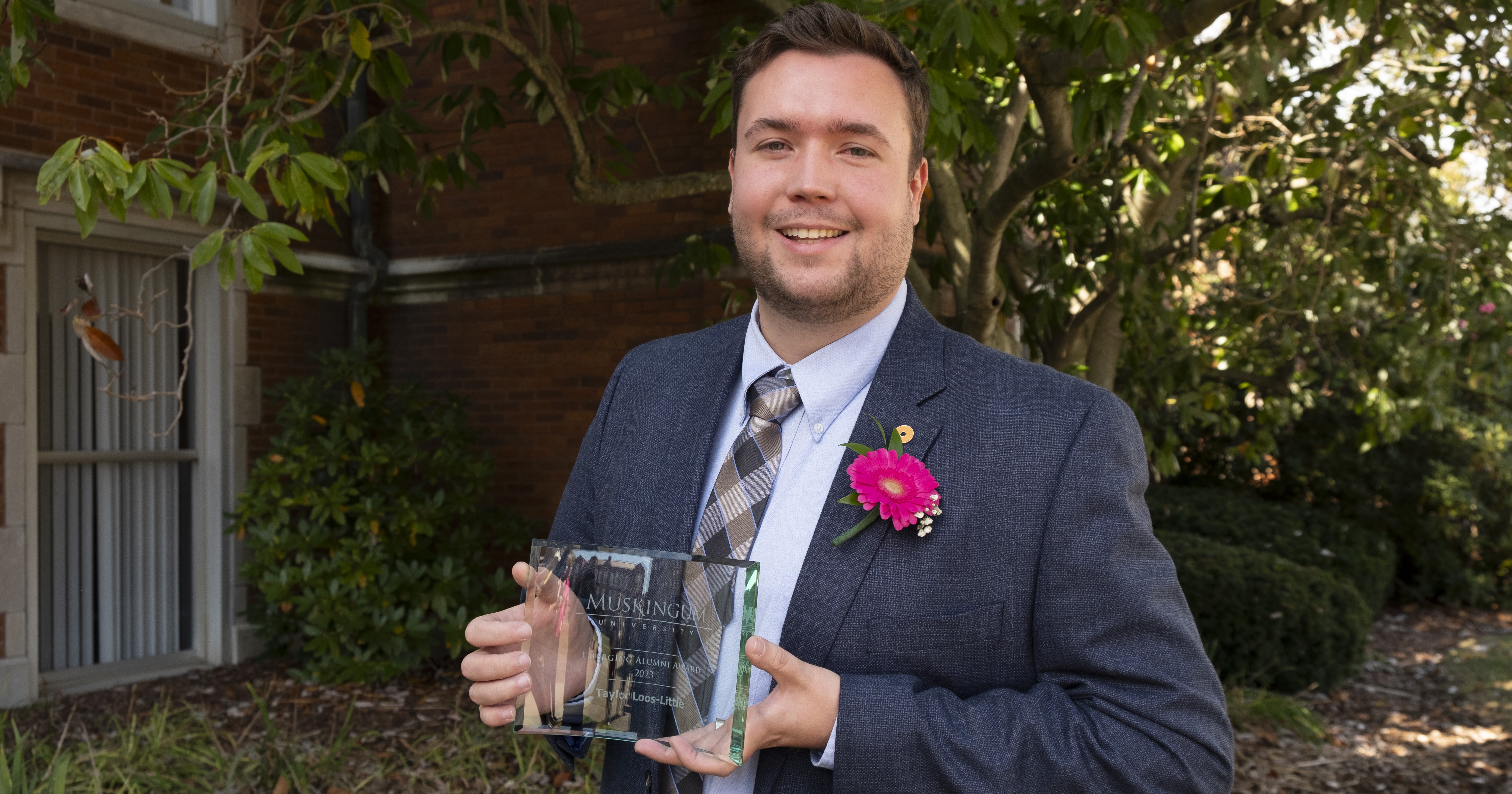 Taylor Loos-Little posing with his Emerging Alumni award at Muskingum University. 